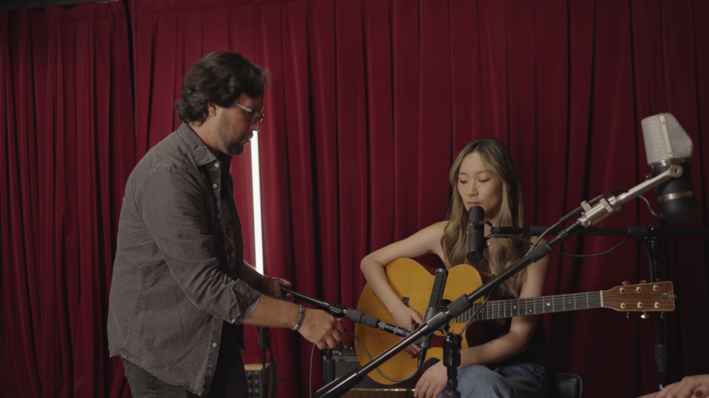 John Escobar adjusts a microphone's placement in front of a guitar. 